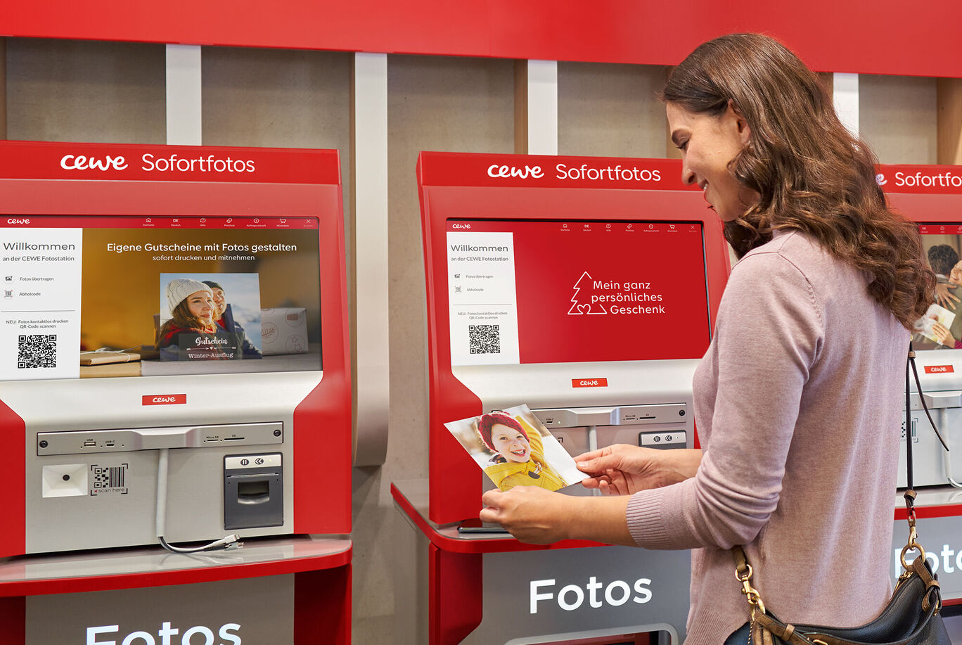 Eine Person steht an einem CEWE Sofortfoto-Automaten und betrachtet ein Foto.