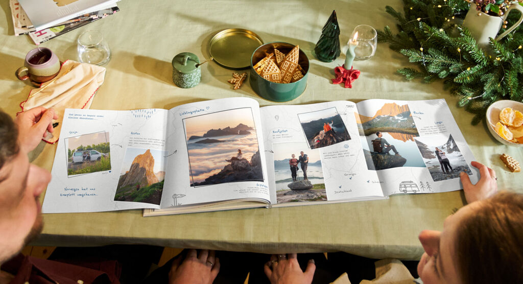 Ein Pärchen bestaunt die vollkommen aufgeklappte Panoramaseite in einem CEWE FOTOBUCH.