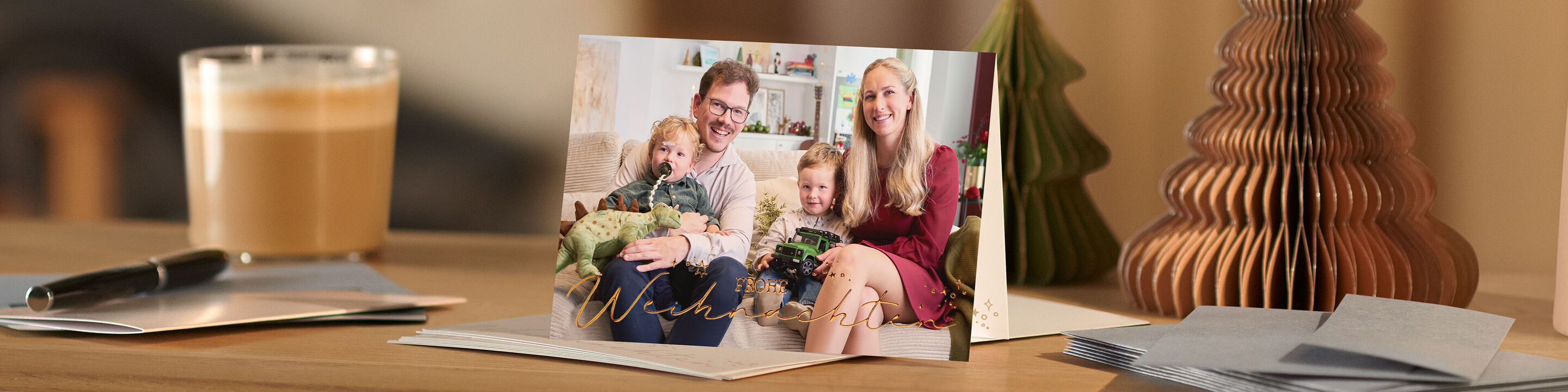 Weihnachtskarte mit Familienfoto steht auf einem Tisch mit Weihnachtsdekoration und Kaffee