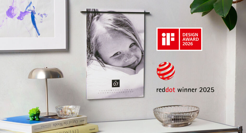 Ein schöner Kalender hängt an der Wand. Darauf ist ein lächelndes Kind mit Sommersprossen zu sehen. Das Bild lässt Freude und Lebensfreude a
