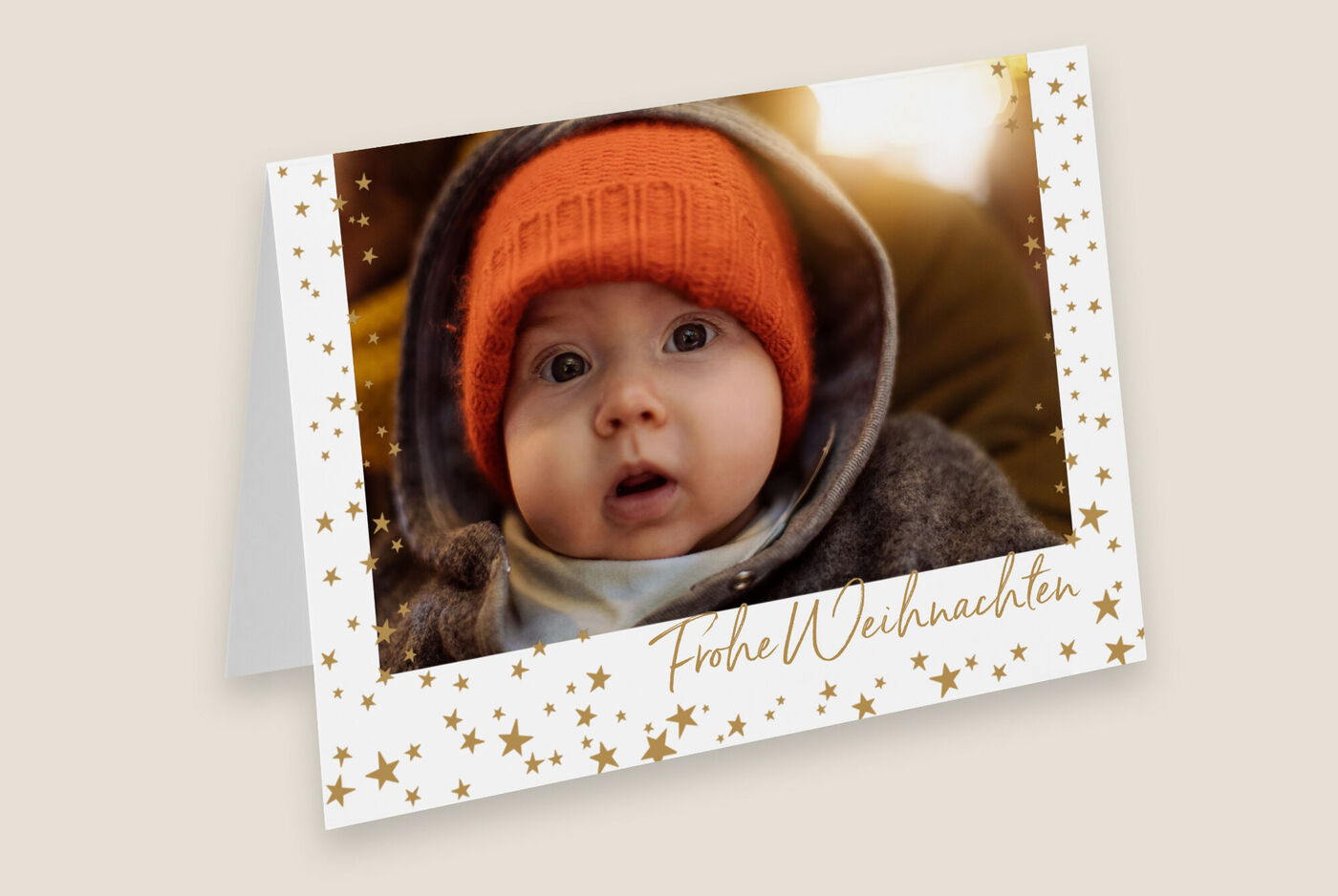 Weihnachtsgrußkarte mit goldenen Sternen und einem Kind mit rotem Hut