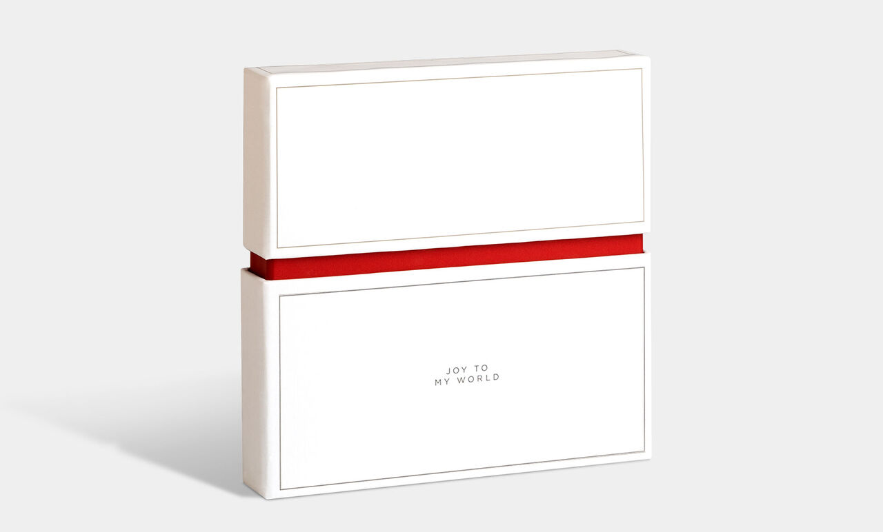 Geschenkverpackung in Weiß mit rotem Band, beschriftet mit 'Joy to my world'