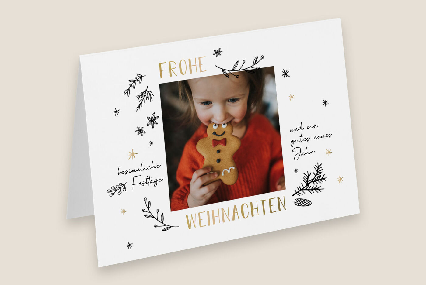 Eine Person in einem roten Pullover hält einen Lebkuchen in Form eines Rentiers. Auf der Karte steht "Frohe Weihnachten und ein gutes neues Jahr".