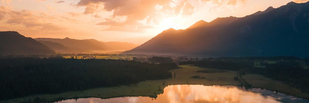 Sonnenuntergang über einen idyllischen See mit Bergen im Hintergrund