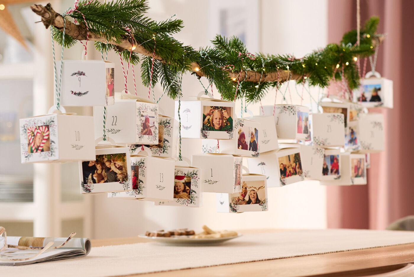 Ein weihnachtlich dekorierter Adventskalender aus 24 einzelnen Schachteln, die mit verschiedenen Fotos bedruckt sind.