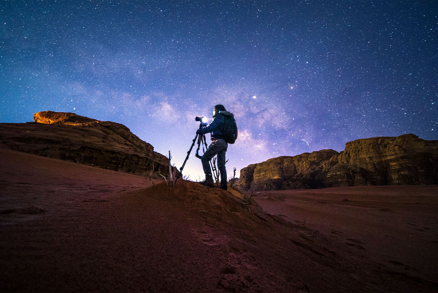 Fotograf bei Nachtaufnahme in der Wüste unter sternenklarem Himmel