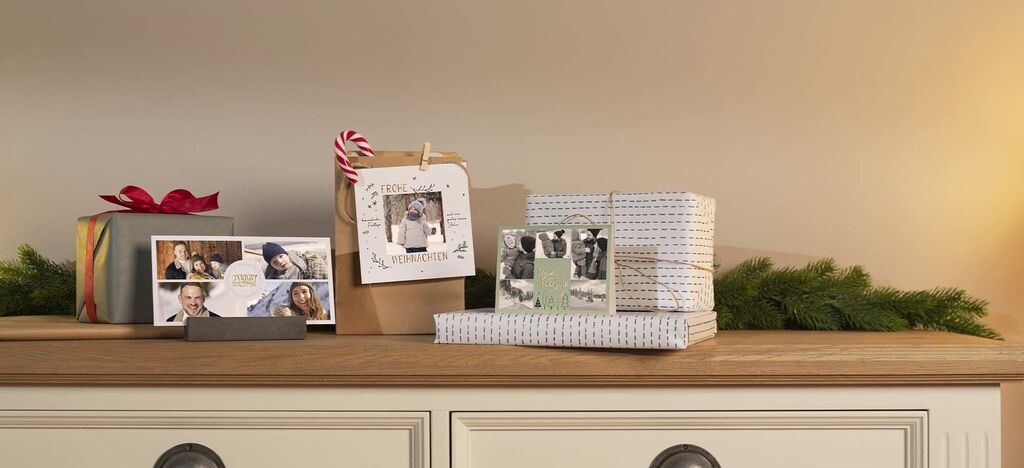 Wundervolle Geschenke und Fotos auf einer Holzkommode dekoriert mit verschiedenen Weihnachtskarten