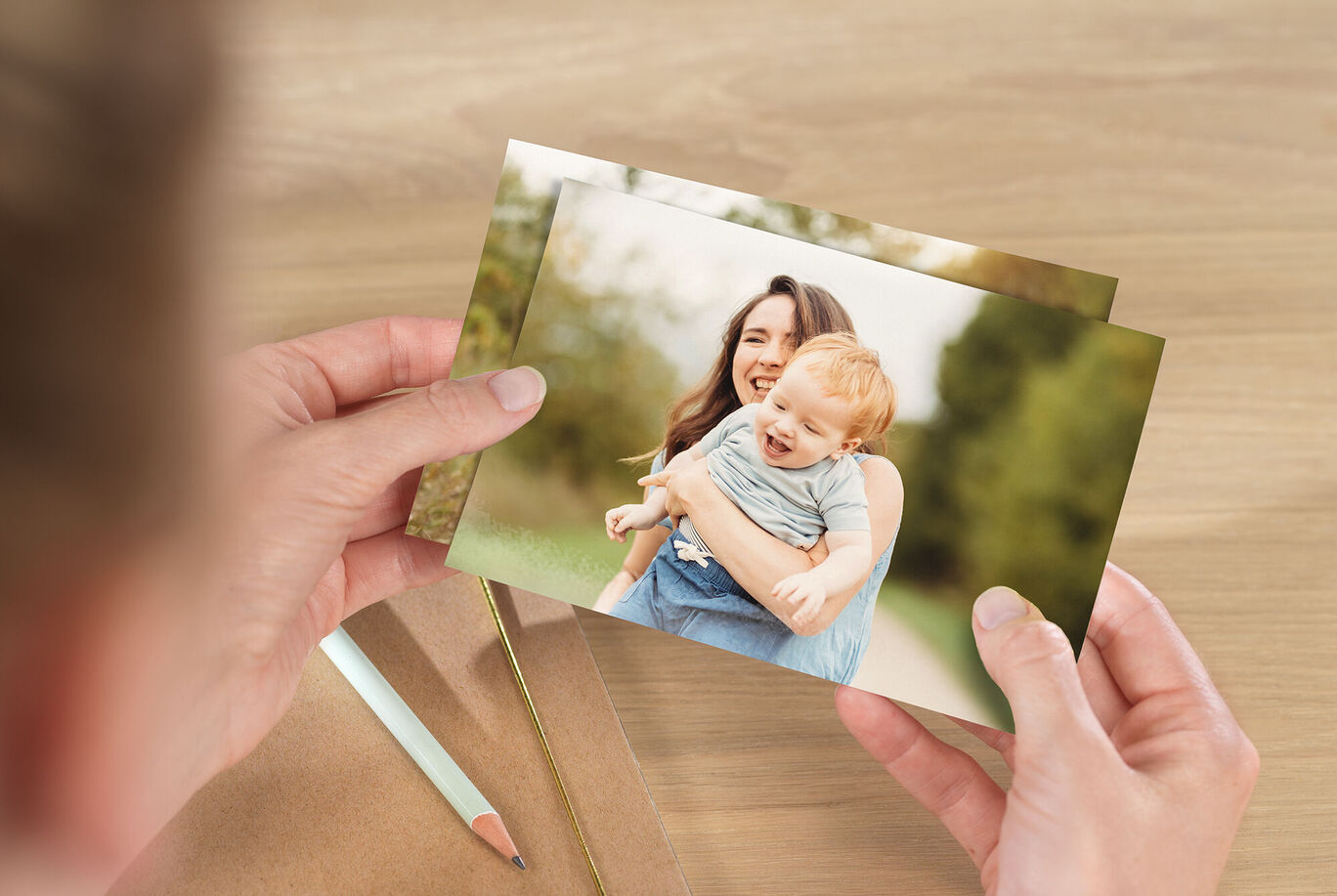 Eine Person hält zwei Fotos in der Hand, auf denen Erinnerungen zu sehen sind