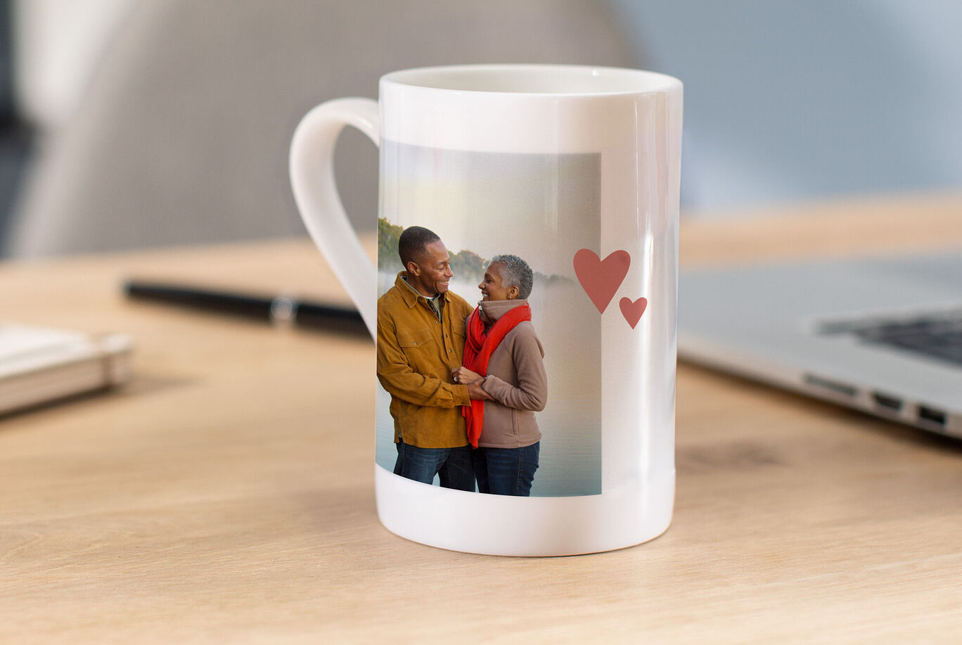 Eine liebevoll gestaltete CEWE Tasse mit einem Paar, das sich anlächelt, vor einer naturnahen Kulisse.
