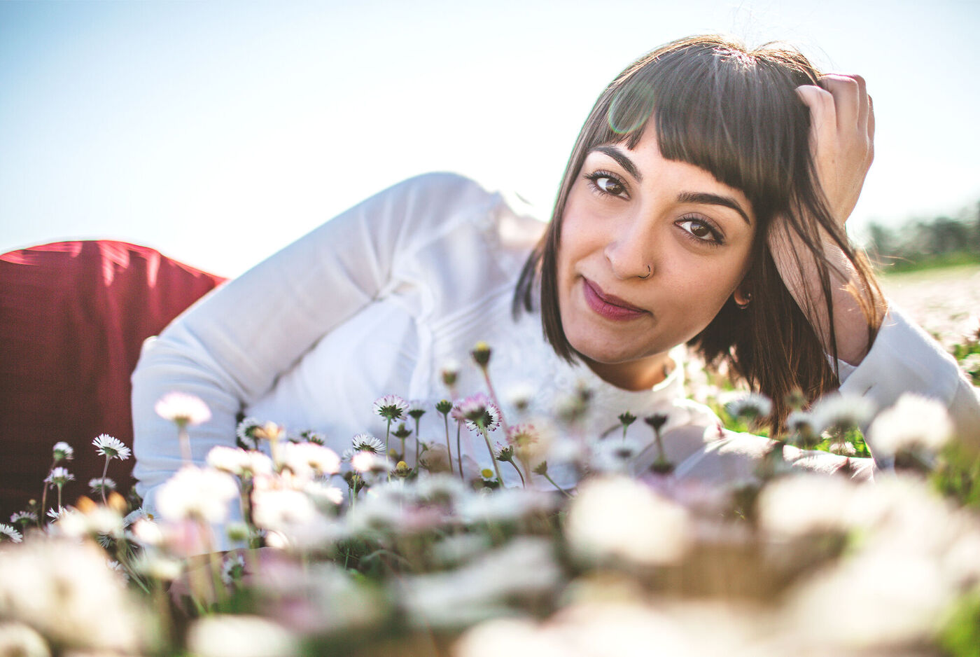 Eine Frau liegt entspannt im Blumenfeld und genießt die Natur.