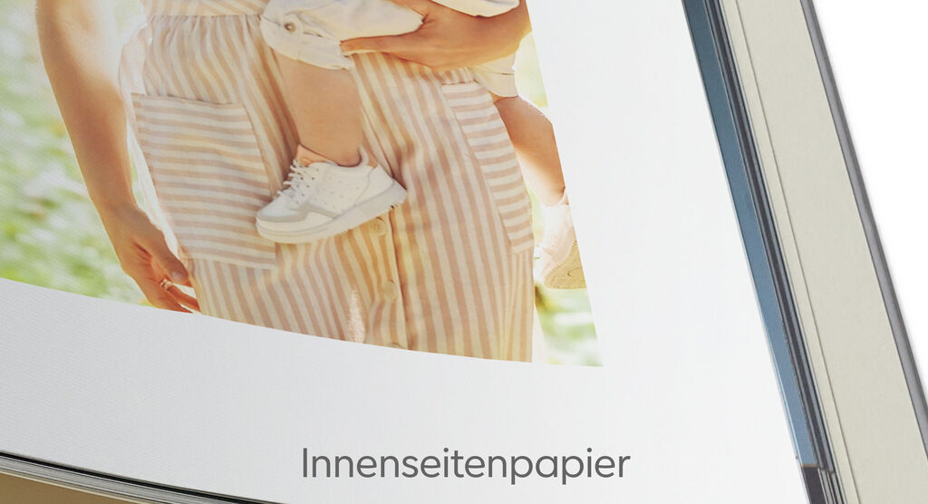 Nahaufnahme eines offenen Fotobuchs mit gestreiftem Cover und leeren Innenseiten.