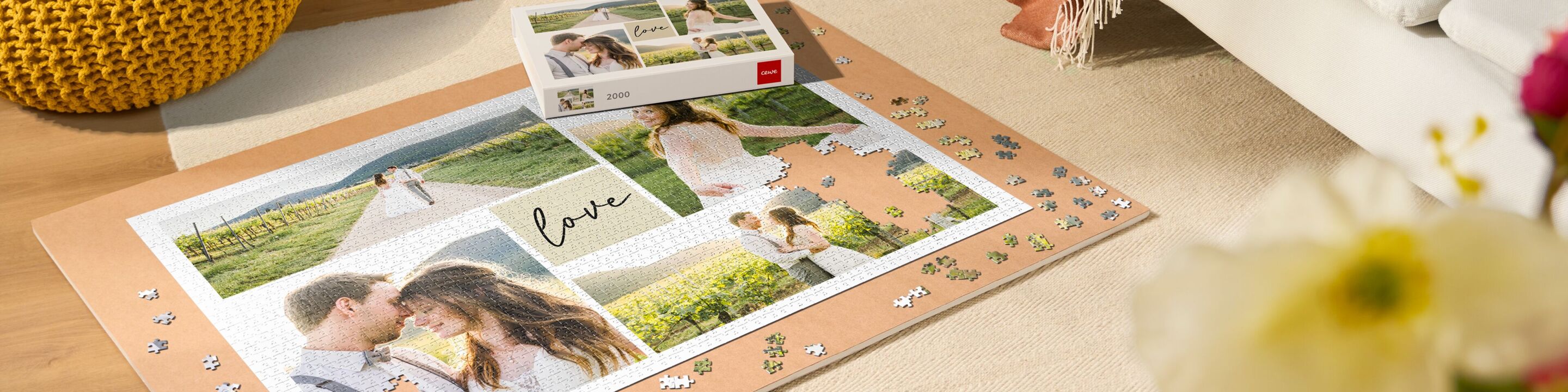 Premium-Fotopuzzle von CEWE mit Bildern eines Paares in einer Weinlandschaft, umgeben von verstreuten Puzzleteilen und Blumen im Vordergrund