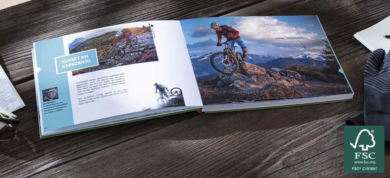 Ein geöffnetes CEWE FOTOBUCH mit Fotos von Mountainbikern in den Bergen. Die Seiten zeigen verschiedene Momente einer Fahrradtour.
