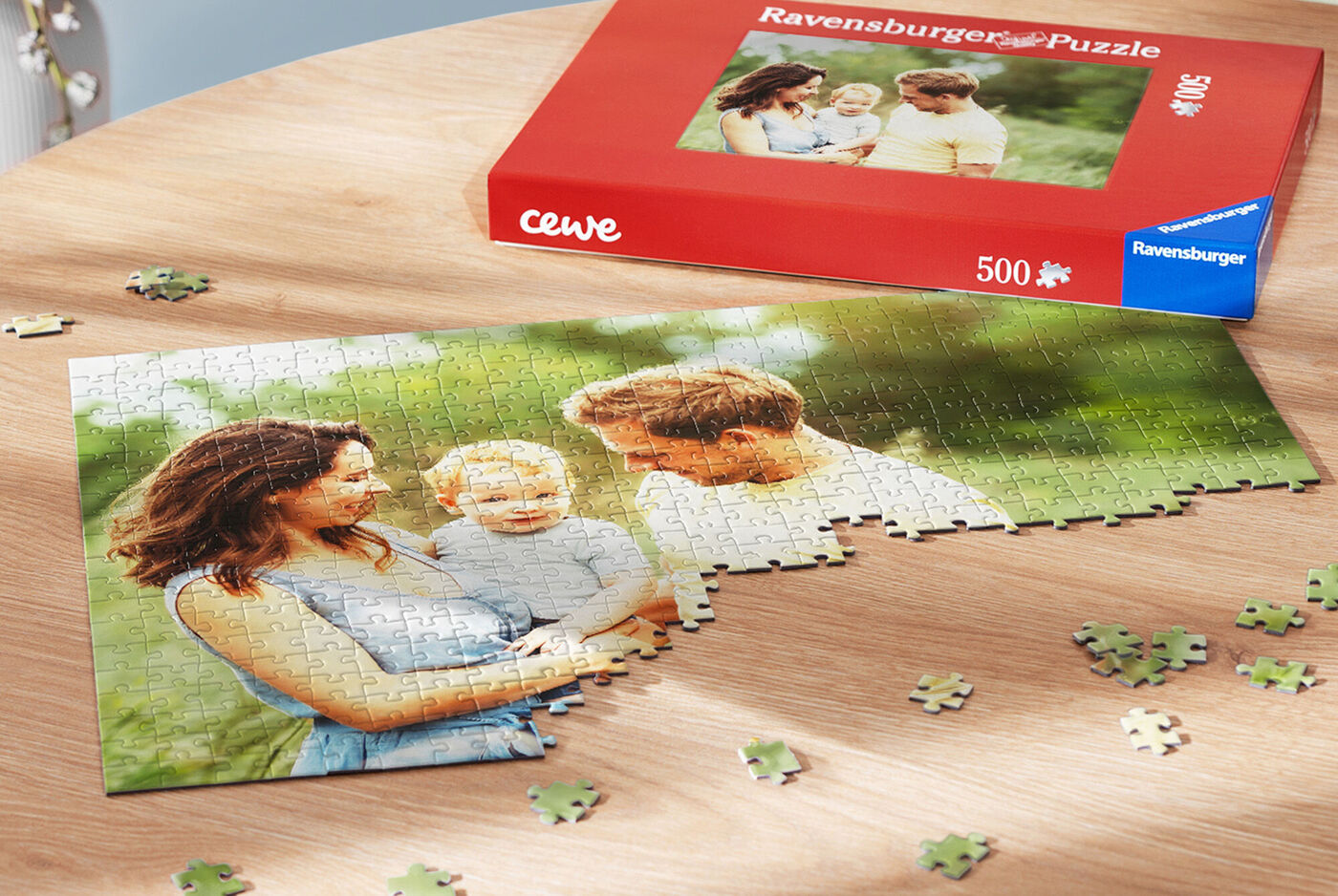 Ein fast fertiges Ravensburger Puzzle zeigt ein glückliches Paar mit einem Kind im Freien. Das Puzzle liegt auf einem Holztisch und einige Teile liegen daneben.
