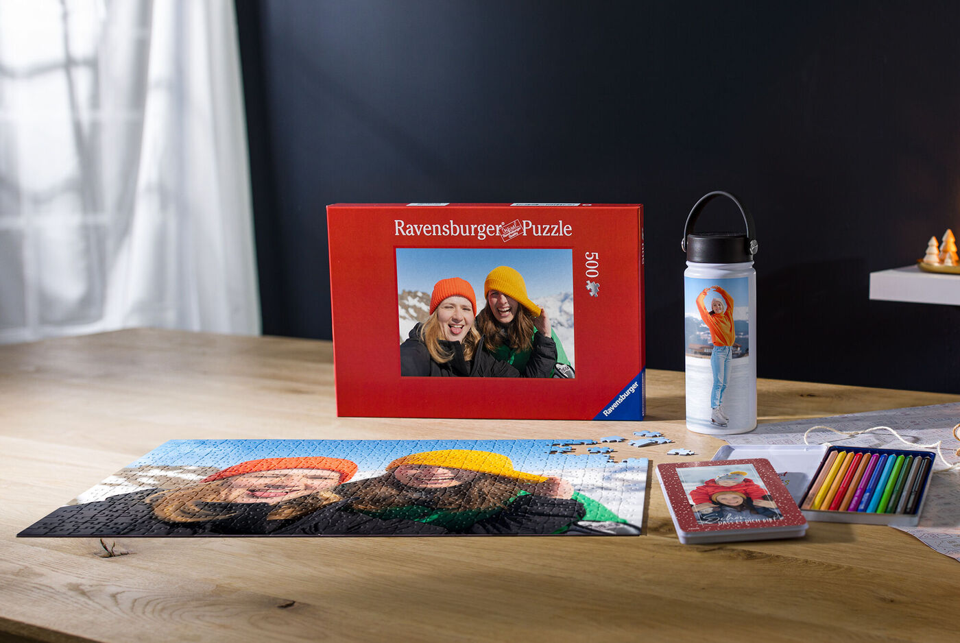 Eine kreative Puzzle-Präsentation mit einem Fotobuch, einer Trinkflasche und Buntstiften auf einem Holztisch