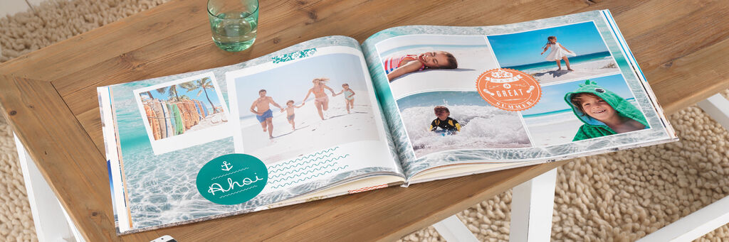 Ein aufgeschlagenes CEWE FOTOBUCH mit Urlaubserinnerungen am Strand, Personen und farbenfrohen Bildern