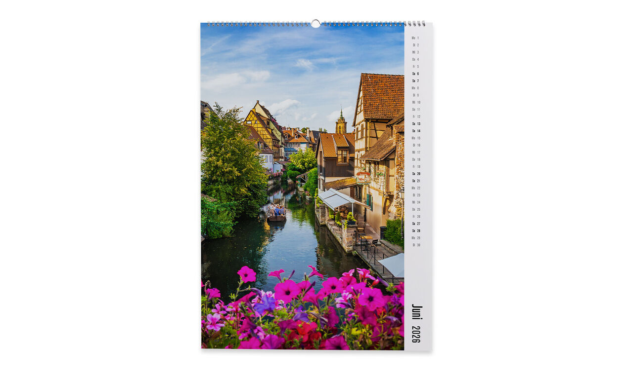 Ein malerischer Kanal mit bunten Blumen und Fachwerkhäusern in einer charmanten Stadt im Juni.