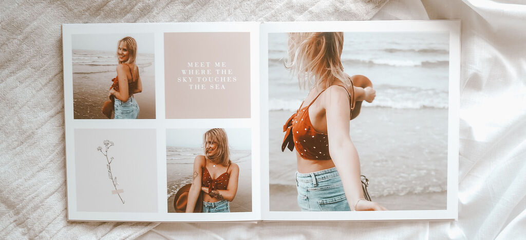 Eine Frau steht am Strand und genießt den Moment mit einem Fotobuch in der Hand.