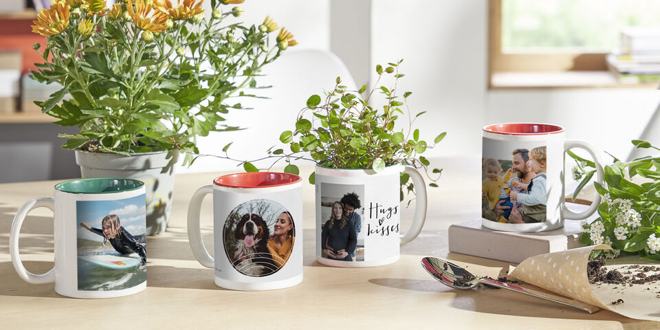 Vier persönliche Tassen mit Fotos von Freunden und Pflanzen auf einem Tisch