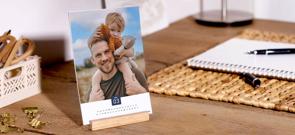 Ein schöner Fotokalender auf einem Tisch mit einer fröhlichen Szene, der 100 % recyceltes Papier verwendet