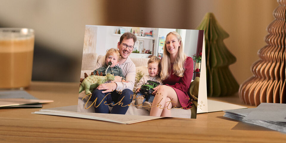 Weihnachtskarte mit Familienfoto steht auf einem Tisch mit Weihnachtsdekoration und Kaffee.