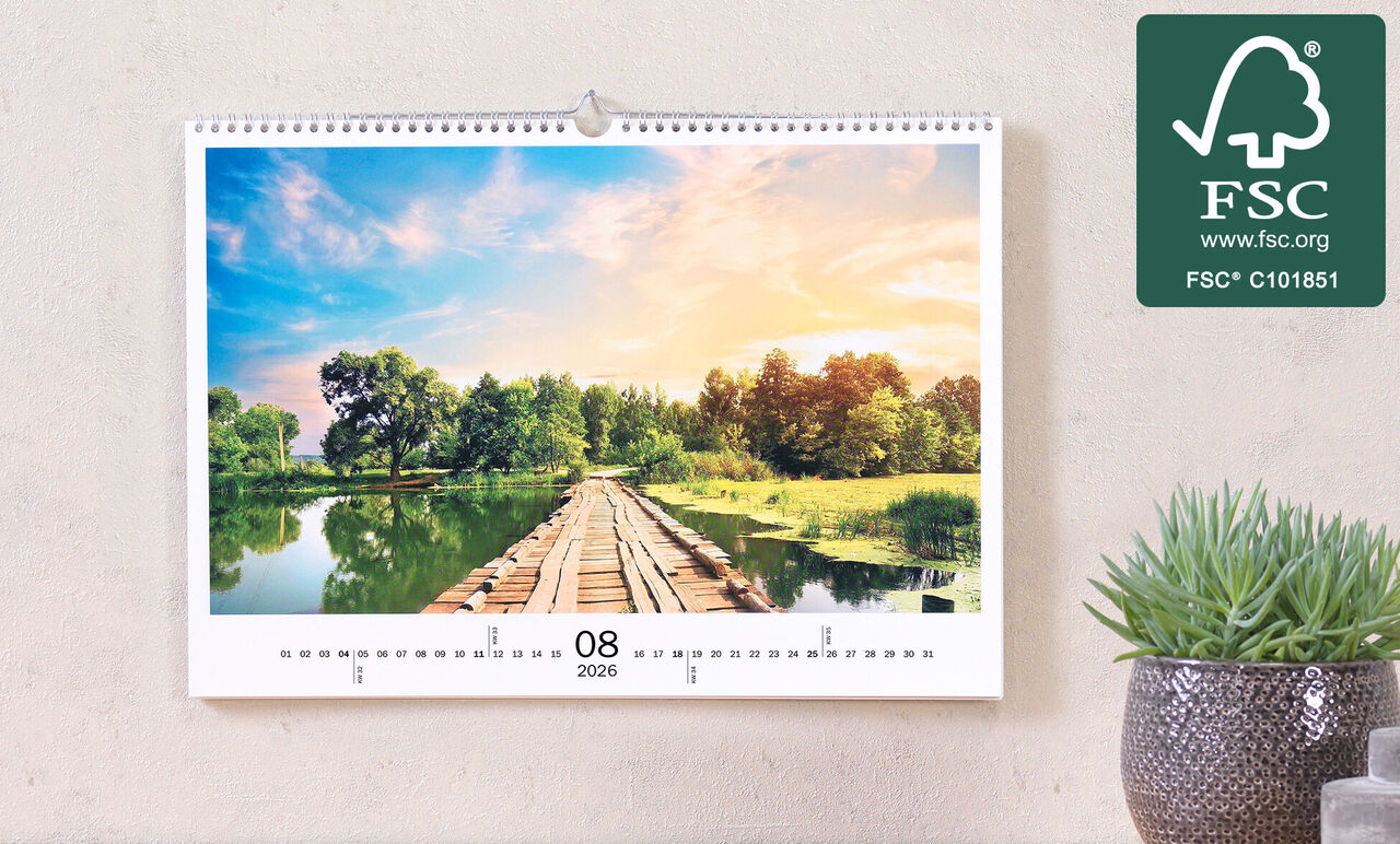 Hängender Fotokalender zeigt eine malerische Landschaft mit Holzsteg über einem ruhigen Gewässer, umgeben von üppigem Grün