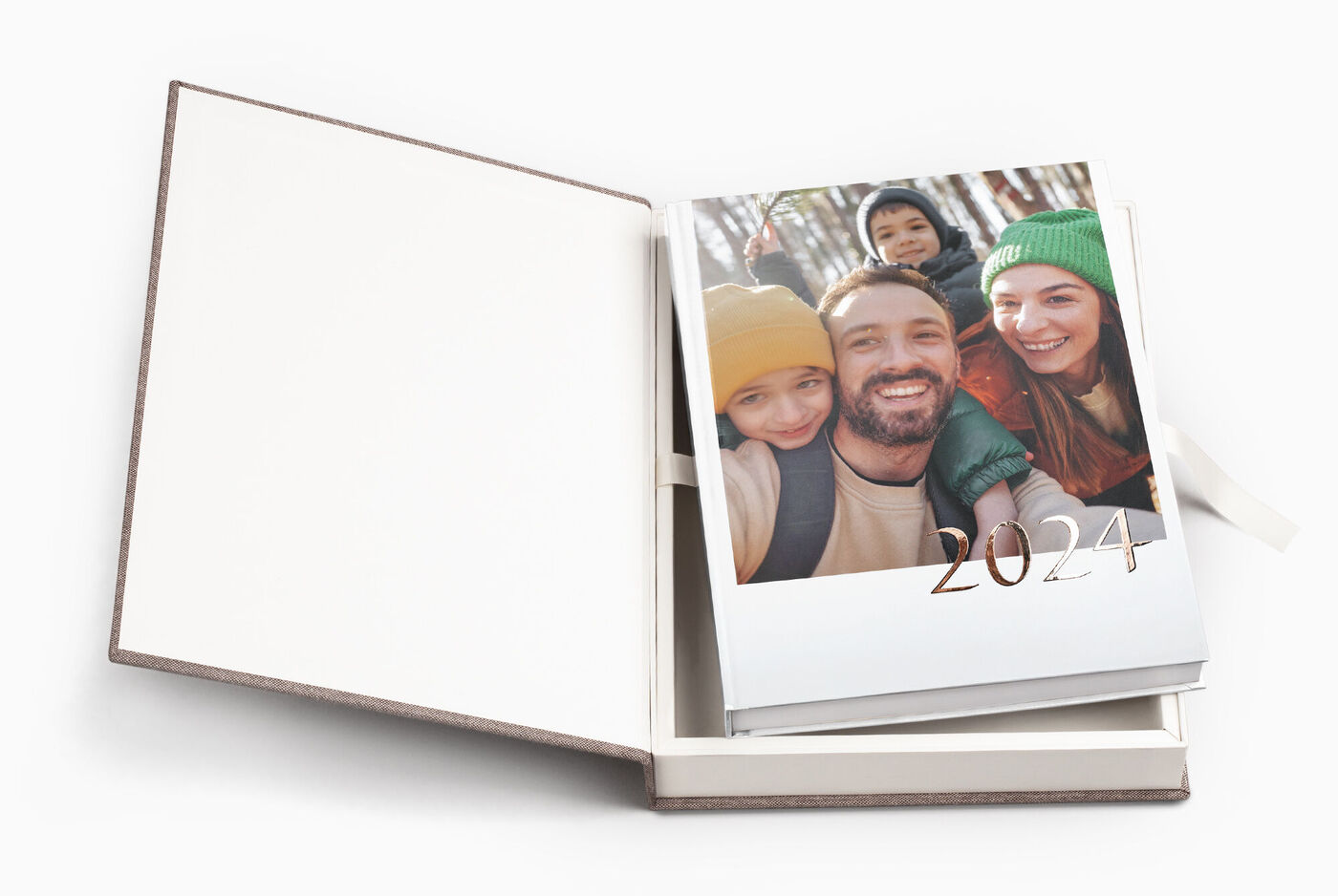 Ein offenes CEWE FOTOBUCH mit einem personalisierten Cover, das die Jahreszahl 2024 zeigt in einer offenen Geschenkbox, passend zum Fotobuch