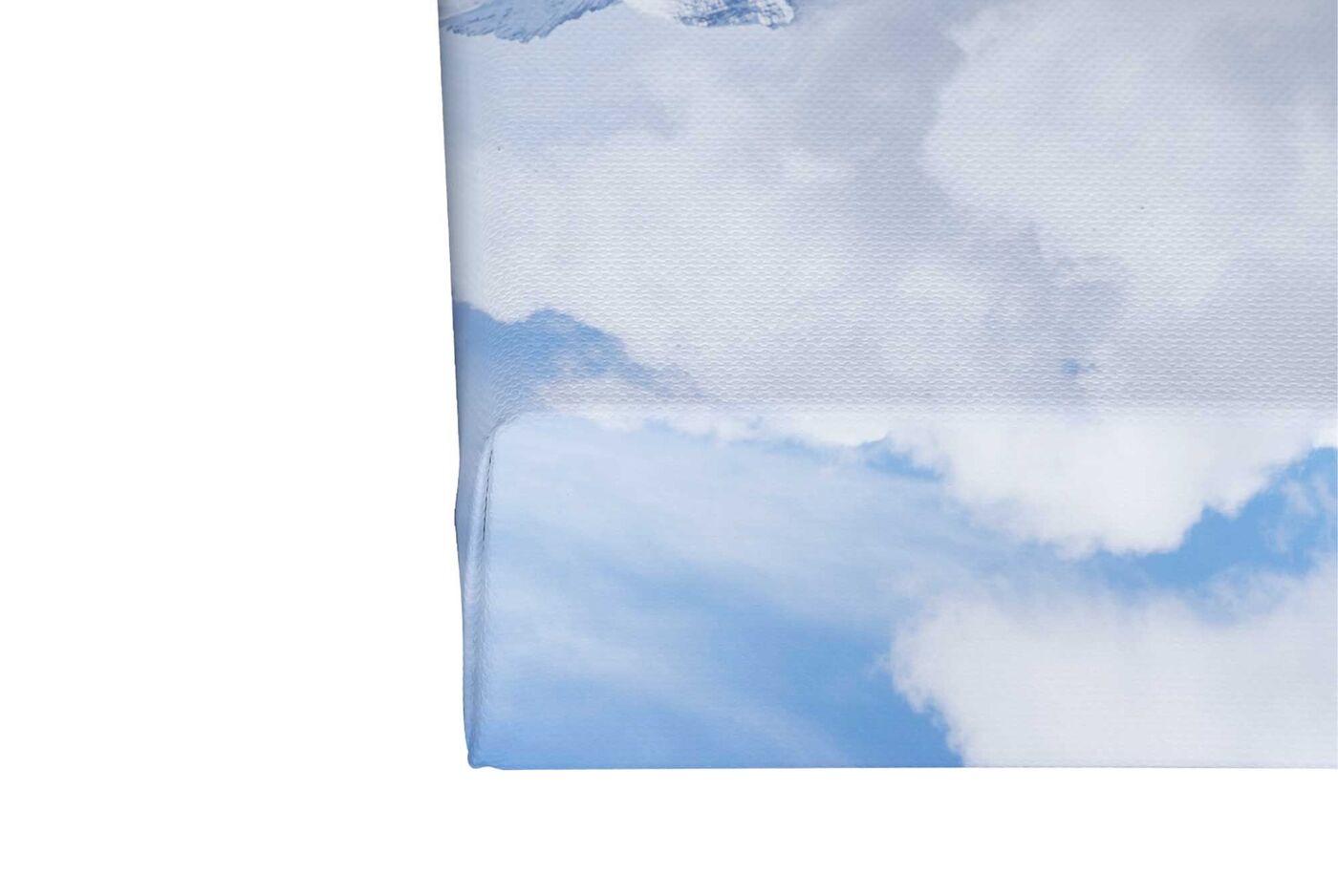 Ein Teil einer Fotoleinwand von CEWE mit einem Bergmotiv mit blauem Himmel auf einem vier Zentimeter starken Keilrahmen.