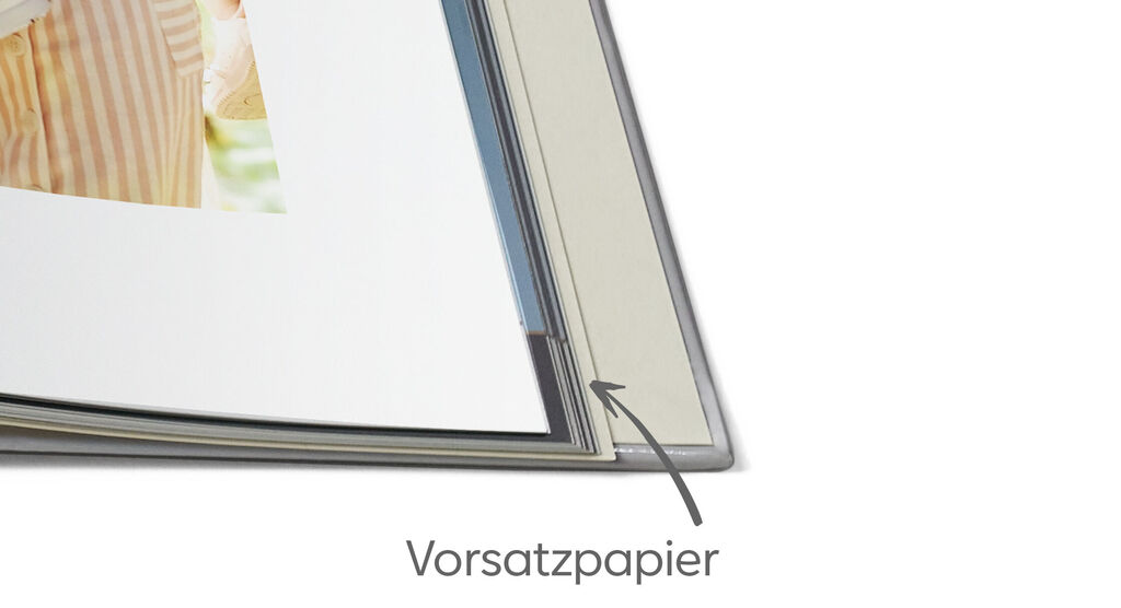 Vorsatzpapier in einem CEWE Fotobuch, leicht beige mit schwarzer Pfeilmarkierung.