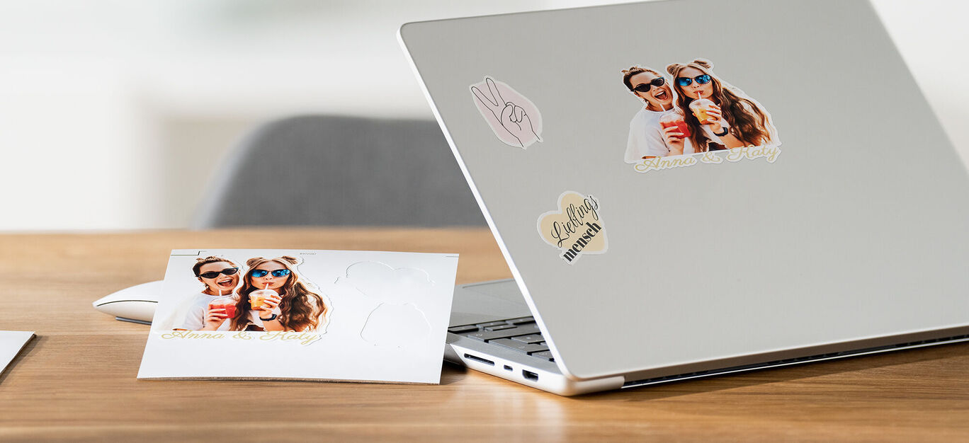 Laptop mit fotorealistischen Aufklebern und Postkarte