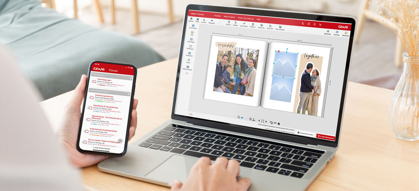 Person gestaltet ein CEWE FOTOBUCH auf einem Laptop und hält ein Smartphone in der Hand