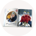 Ein offenes Fotobuch zeigt liebevolle Winterurlaubserinnerungen mit fröhlichen Kindern und winterlicher Landschaft