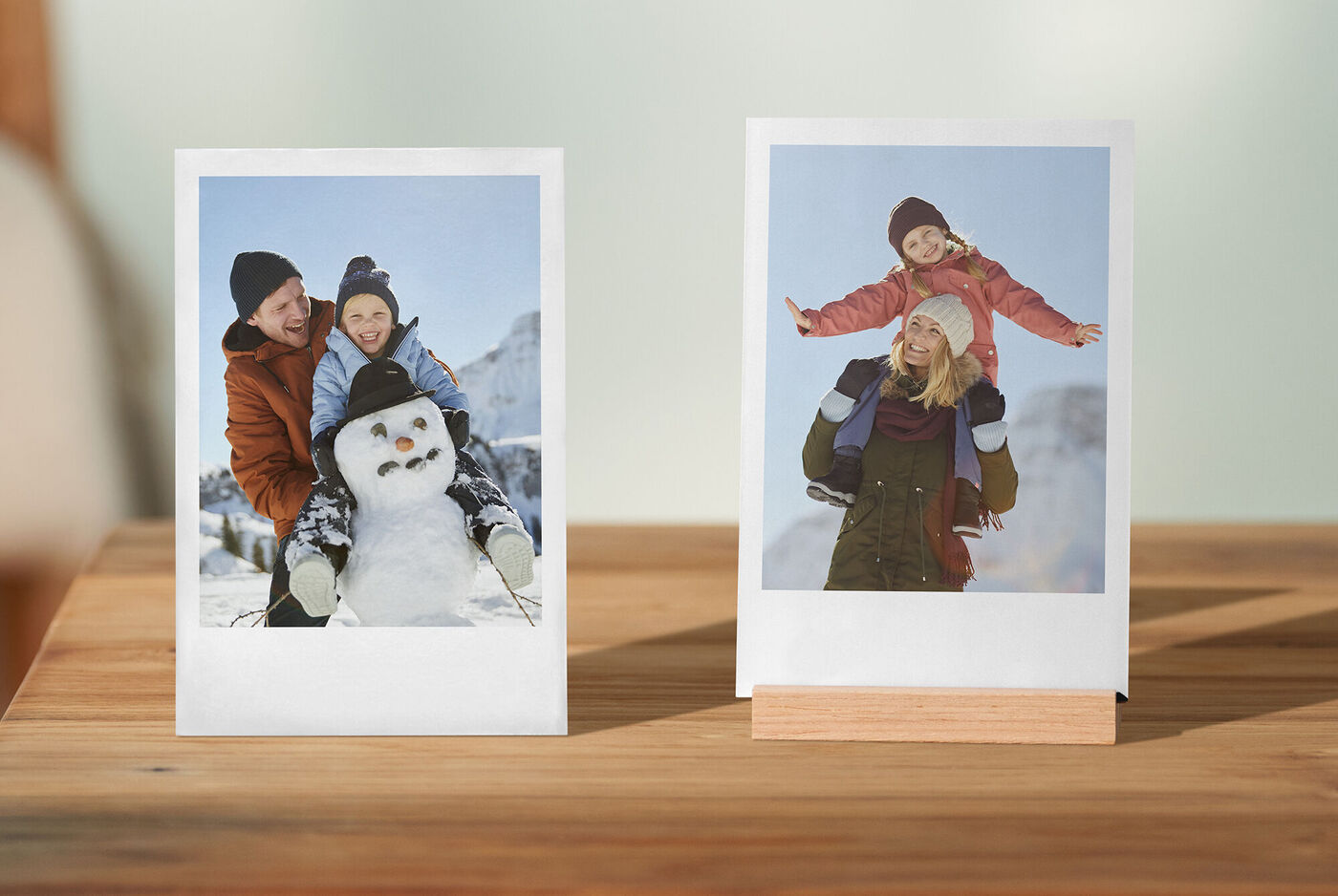 Zwei fröhliche Kinder im Schnee, ein Junge auf dem Rücken eines Erwachsenen und ein Mädchen, das hochgehoben wird.