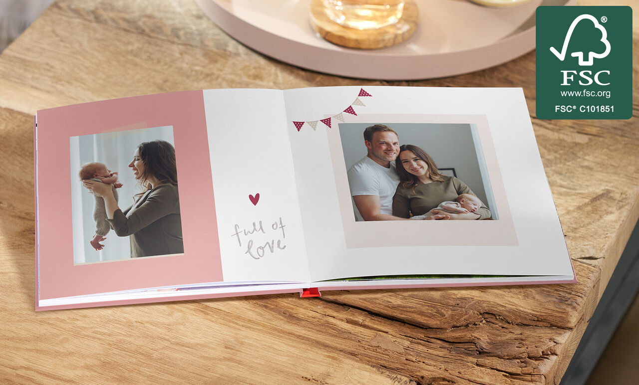 Offenes CEWE FOTOBUCH mit Fotos von Eltern und Neugeborenem