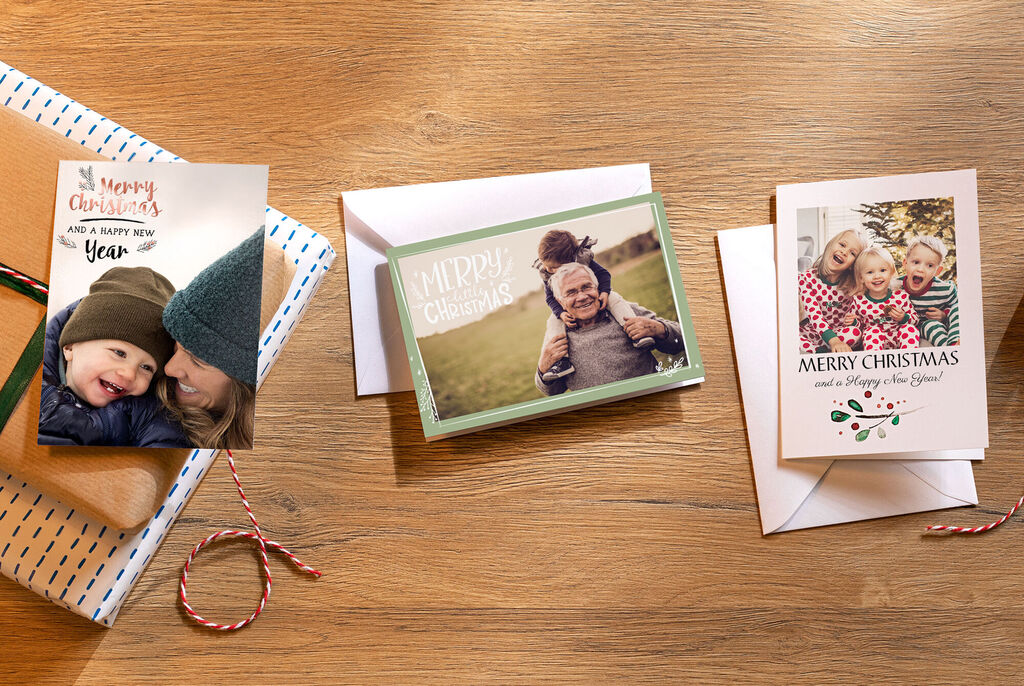 Drei Weihnachtskarten liegen auf einem Tisch. Die Eine Karten haben unterschiedliche Designs und Formate. Sie zeigen alle Familienfotos.