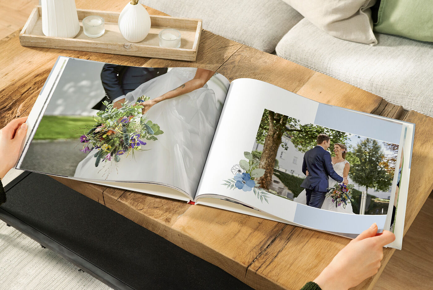 Zwei Personen blättern durch ein CEWE Fotobuch mit Hochzeitsfotos, umgeben von einer warmen Holzoberfläche.