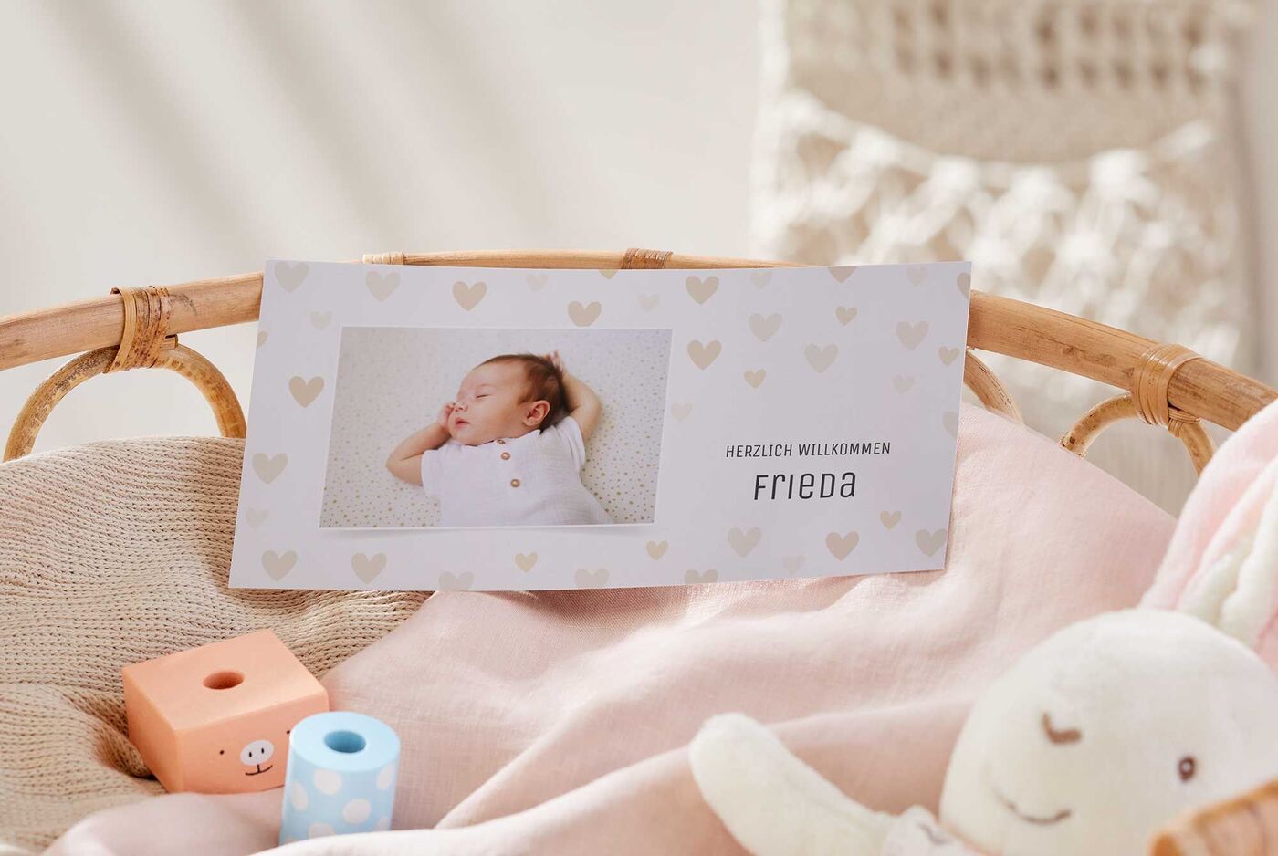 Ein liebevoll gestaltetes Willkommensschild für ein Neugeborenes. Es liegt auf einer weichen Decke in einem Kinderkorb.