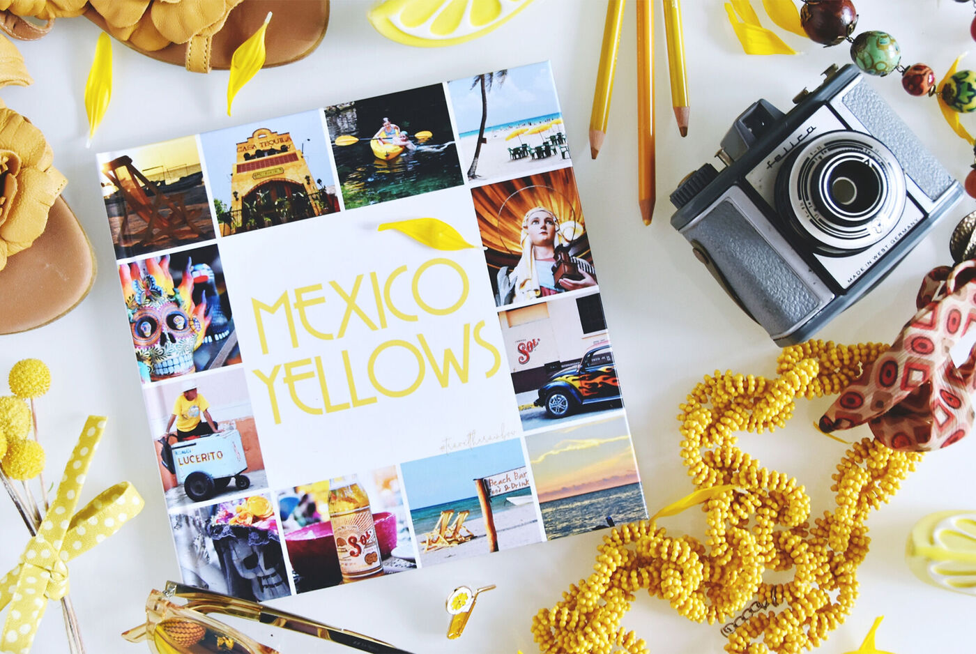 Farbenfrohes Fotobuch mit dem Titel "Mexico Yellows" auf einem Tisch, umgeben von gelben Accessoires und einer Kamera