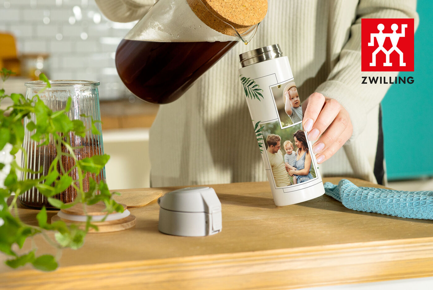 Eine Person gießt Kaffee aus einer Kanne in einen personalisierten Thermobecher mit Fotos.