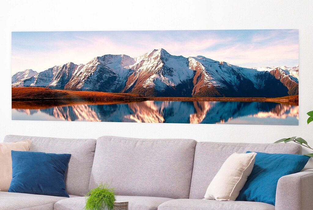 Schönes Panorama eines Gebirges mit schneebedeckten Gipfeln und spiegelndem Wasser im Vordergrund